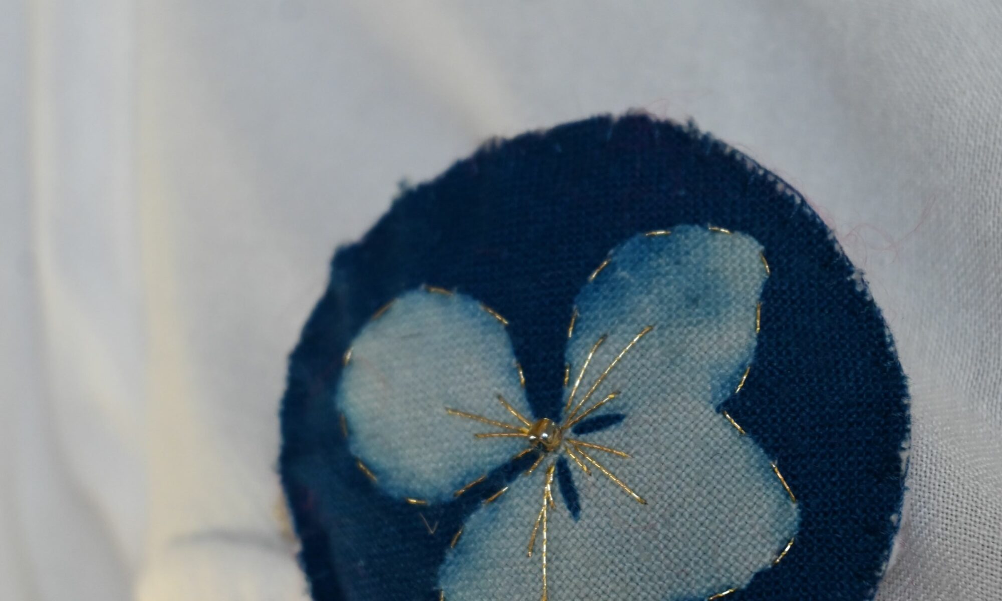 Broche imprimée cyanotype sur tissu brodé au fil d'or, réprésente une fleur d'hortensia