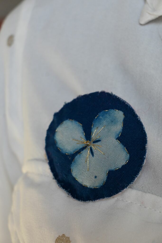 Broche imprimée cyanotype sur tissu brodé au fil d'or, réprésente une fleur d'hortensia