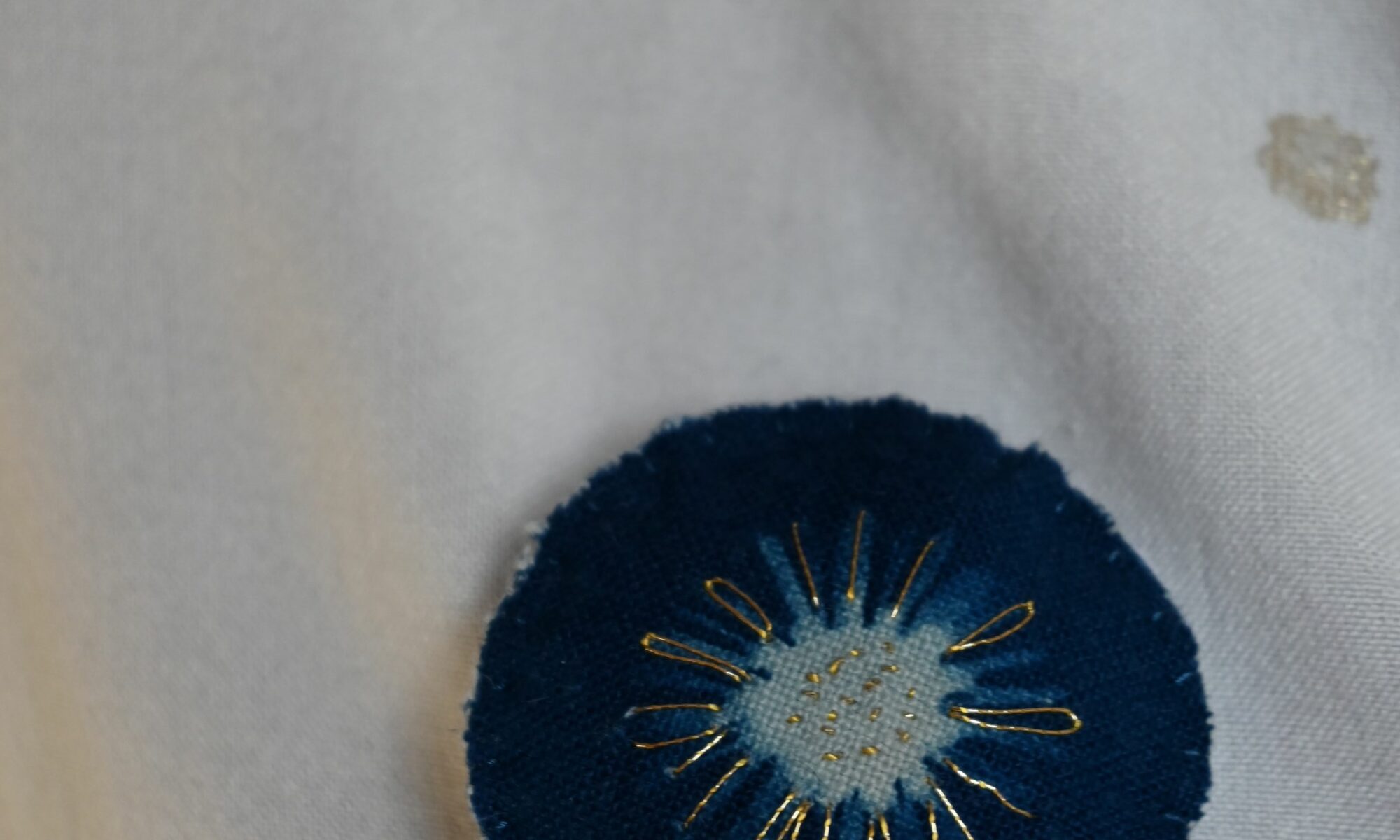 Broche imprimé en cyanotype sur tissu brodé au point de sable