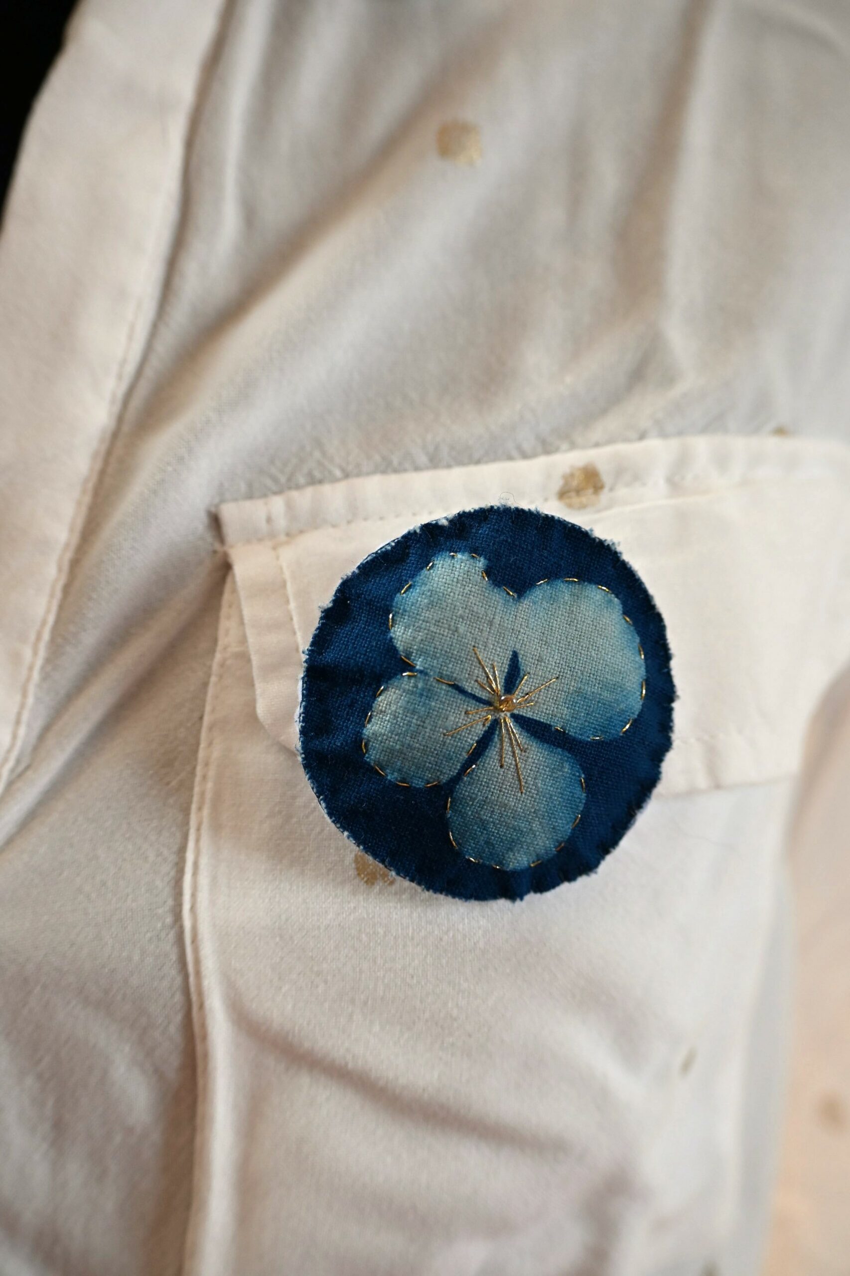 Broche impression cyanotype d'une fleur d'hortensia, brodée de fil d'or et perles dorées