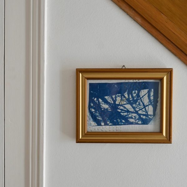 Cadre cyanotype posée dans une montée d'escalier, broderie au fil d'or