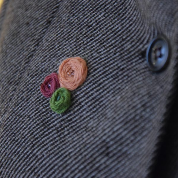 Point de rose avec perles sur une veste réalisé à l'aiguille